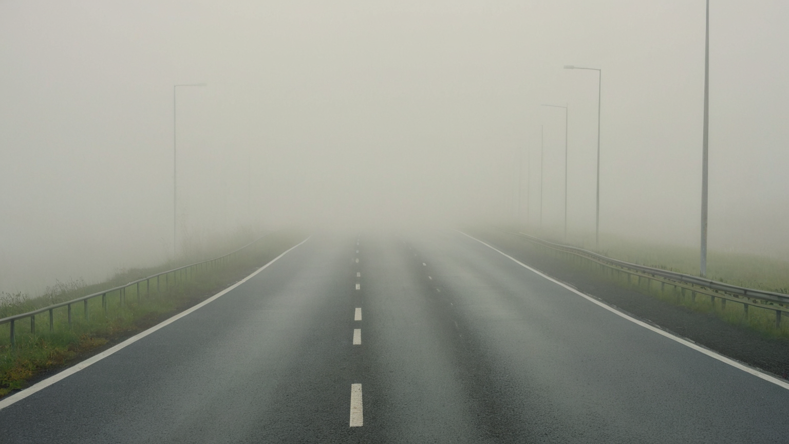 A divided highway fading into a uniform bank of fog