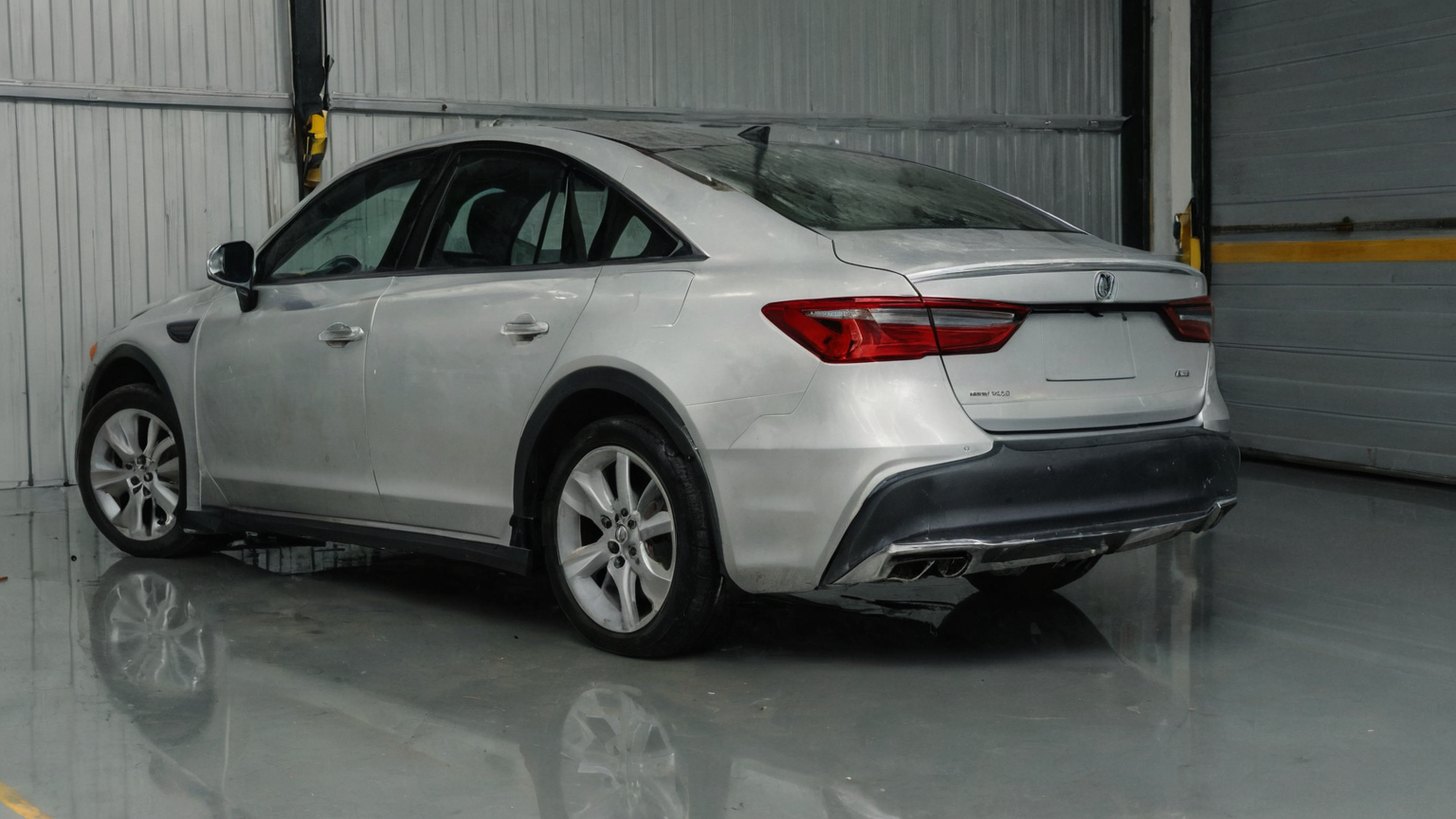 A silver sedan parked in a clean indoor vehicle inspection bay